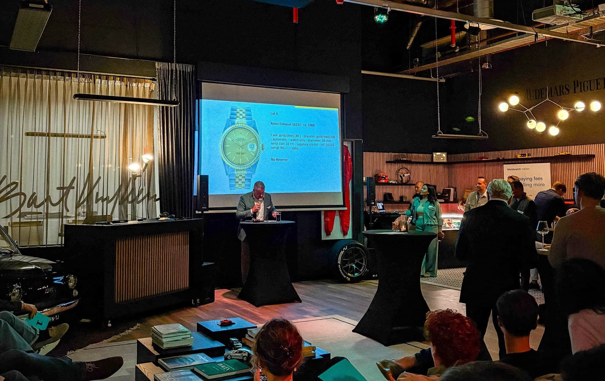 The auctioneer at the Worldwatch launch calling lot 3, a Rolex Datejust, shown on the screen behind him